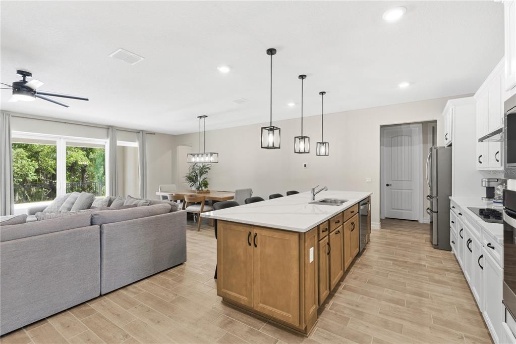 An open-concept kitchen features a wooden island with a white countertop and pendant lighting — 6035 BLUE VIEW WAY, ST CLOUD, FL