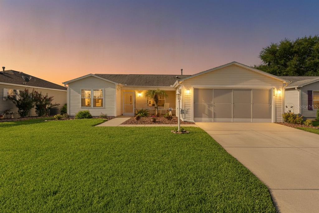 A single-story house with light siding, a two-car garage, and a green front lawn — 8397 SE 177TH BARTRAM LOOP, THE VILLAGES, FL