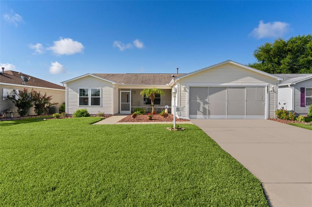 A single-story house with light siding, a concrete driveway, and a front lawn — 8397 SE 177TH BARTRAM LOOP, THE VILLAGES, FL
