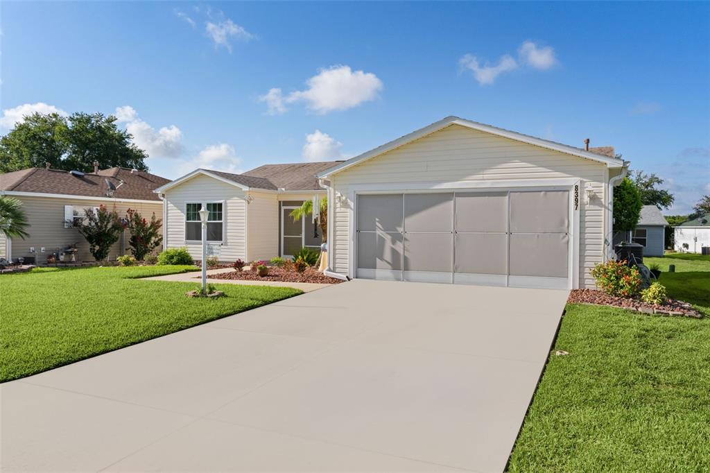 A single-story house with light siding, a concrete driveway, and a covered garage door — 8397 SE 177TH BARTRAM LOOP, THE VILLAGES, FL