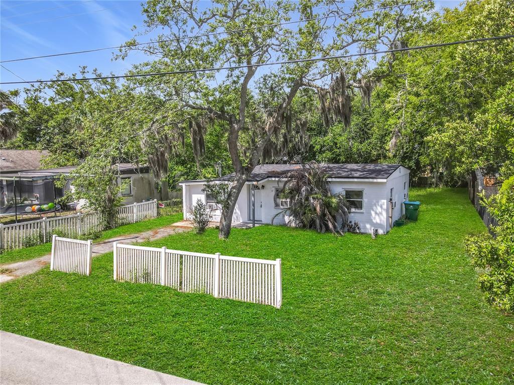 A white single-story house with a large tree in the front yard and white fencing — 1312 JARECKI AVENUE, HOLLY HILL, FL