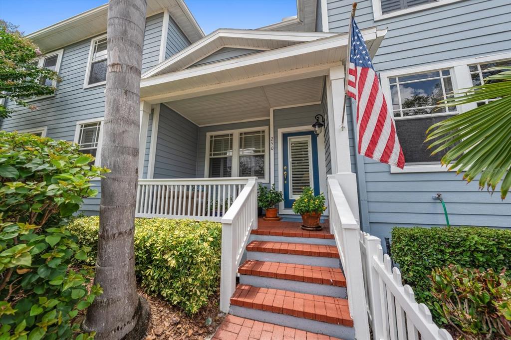 A blue house exterior features a front porch with brick steps and an American flag — 250 2ND AVENUE SW, LARGO, FL
