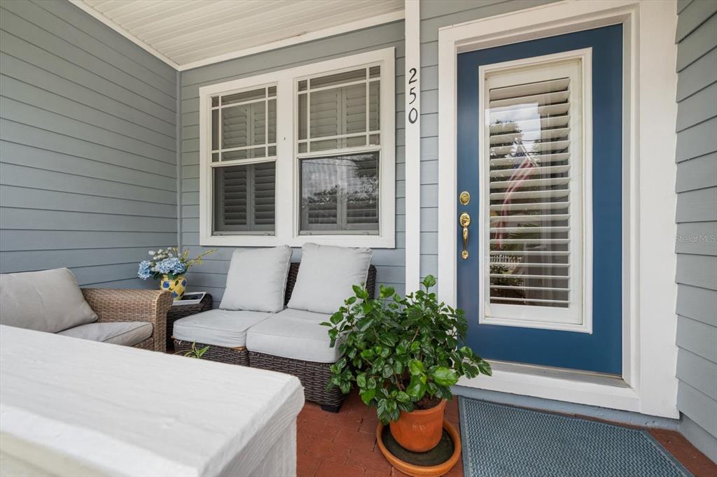 A covered porch features blue siding, a blue front door, wicker seating, and a potted plant — 250 2ND AVENUE SW, LARGO, FL