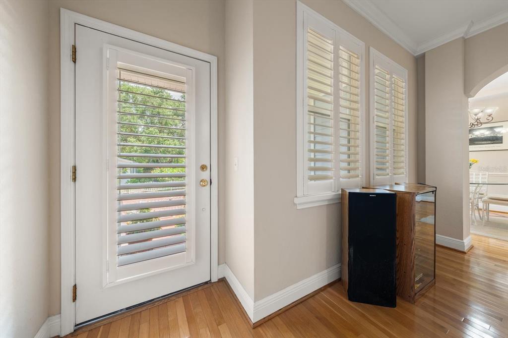 A room with hardwood floors, a white door with shutters, and two windows with shutters — 250 2ND AVENUE SW, LARGO, FL