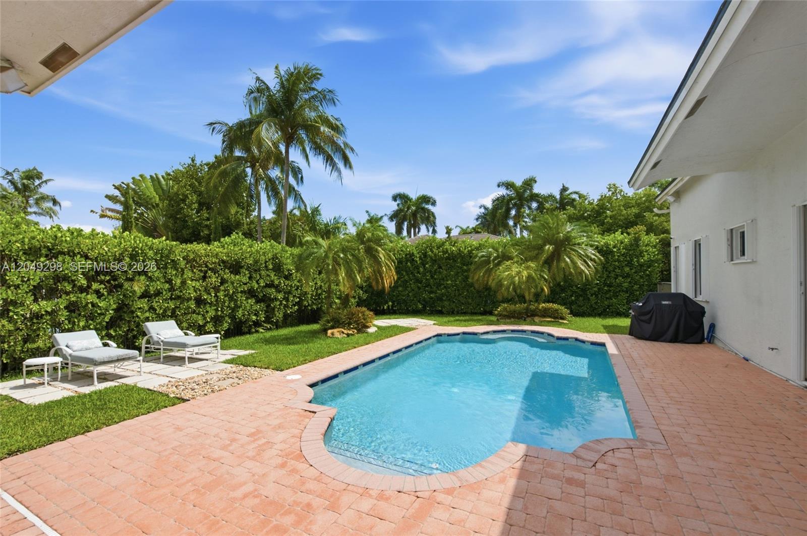 A backyard features a swimming pool, a brick patio, lounge chairs, and lush landscaping — 2542 Eagle Run Dr, Weston FL 33327, WESTON, FL