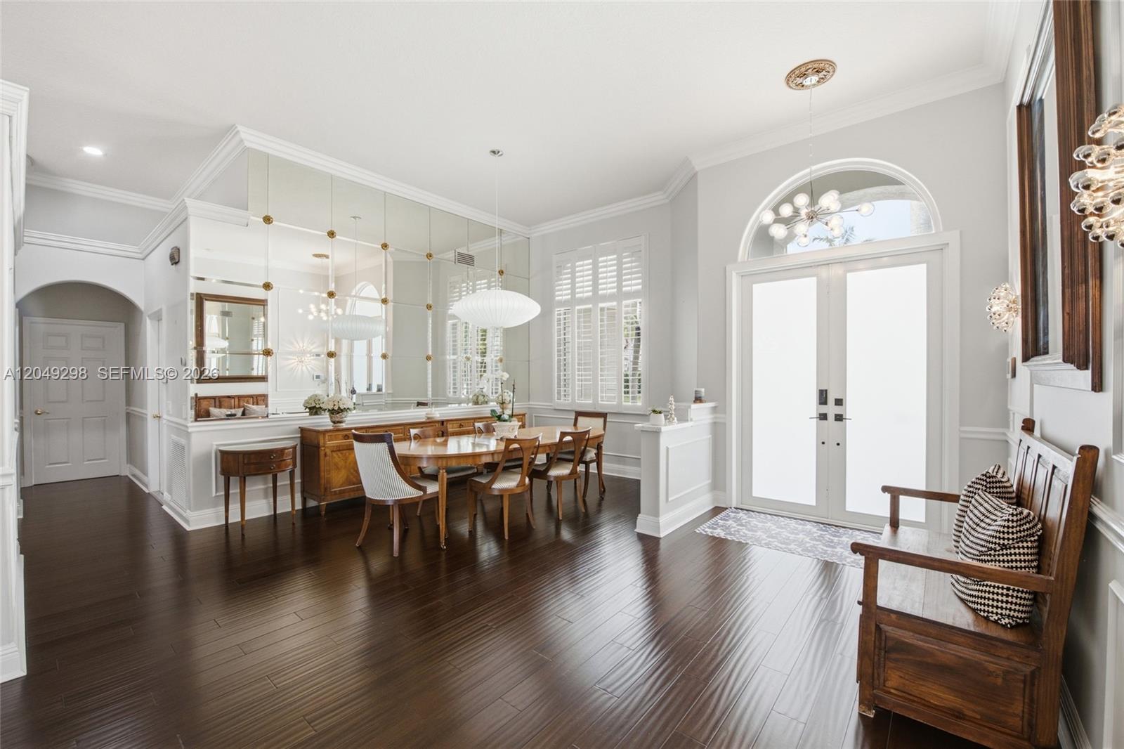 A dining area features a mirrored wall, dark wood floors, and a glass-paned double door — 2542 Eagle Run Dr, Weston FL 33327, WESTON, FL