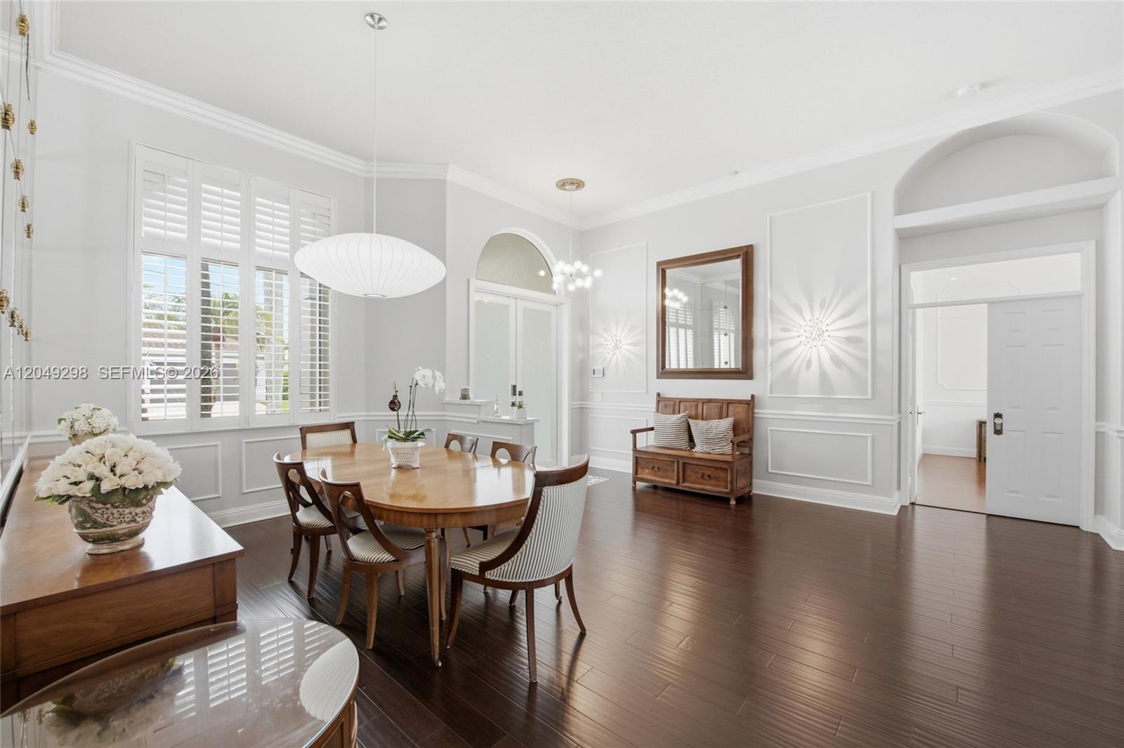 A dining room features a wooden table, striped chairs, hardwood floors, and wall molding — 2542 Eagle Run Dr, Weston FL 33327, WESTON, FL
