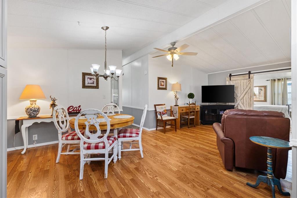 A dining area and living space feature wood-look flooring, white walls, and a ceiling fan — 732 ROYAL PALM AVENUE, LADY LAKE, FL