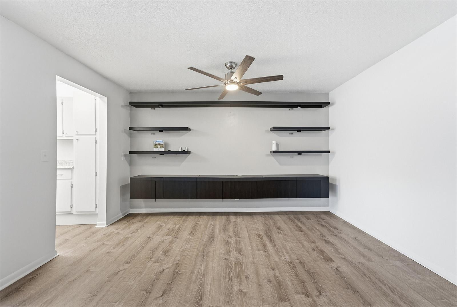 A living room features dark floating shelves and cabinets against a light gray wall — 355 Main Boulevard # C, Boynton Beach FL 33435, BOYNTON BEACH, FL