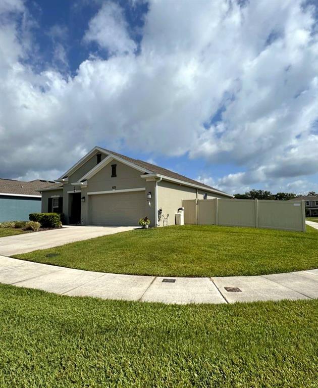 A tan single-story house with a two-car garage and a white vinyl privacy fence — 1969 TURTLE DOVE LANE E, KISSIMMEE, FL