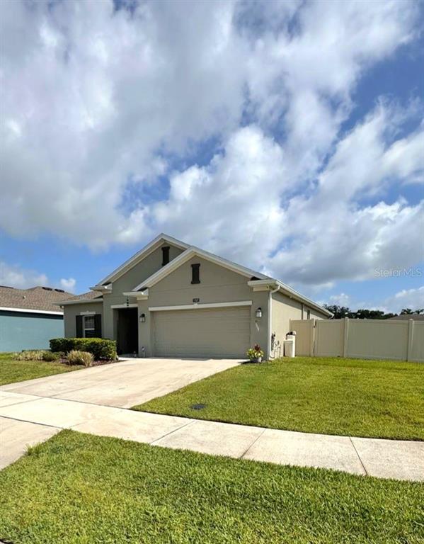 A single-story house with a beige exterior, a two-car garage, and a white vinyl fence — 1969 TURTLE DOVE LANE E, KISSIMMEE, FL
