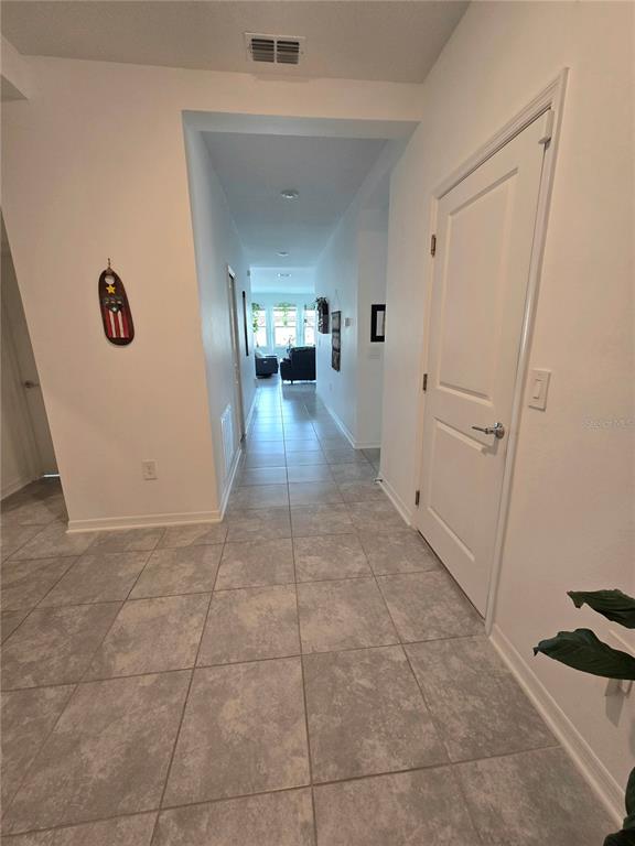 A tiled hallway leads from an entryway toward a living area with large windows — 1969 TURTLE DOVE LANE E, KISSIMMEE, FL
