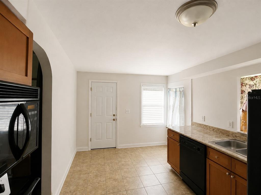 A kitchen with light-colored walls, tile flooring, wood cabinets, and a black dishwasher — 1044 58TH AVENUE N, ST PETERSBURG, FL