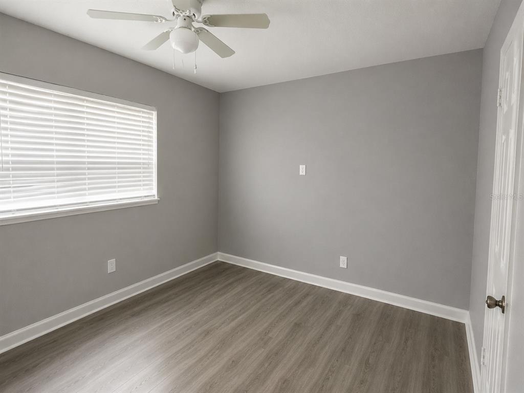 An empty bedroom with gray walls, wood-look flooring, a ceiling fan, and white blinds — 1044 58TH AVENUE N, ST PETERSBURG, FL