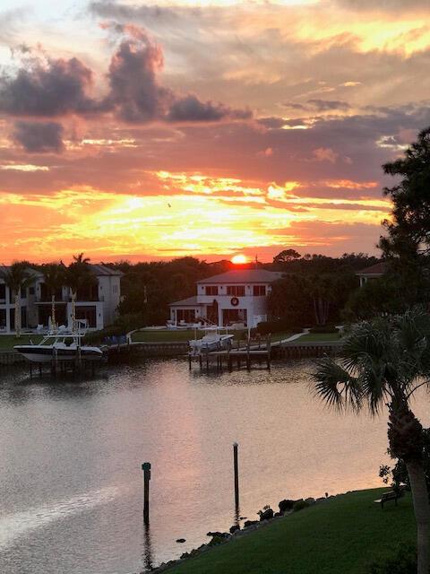 A sunset view over a canal with houses, boat docks, and palm trees — 2201 Marina Isle Way # 403, Jupiter FL 33477, JUPITER, FL