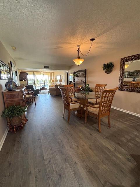 A dining area with a glass table and wooden chairs sits beside a living room — 2201 Marina Isle Way # 403, Jupiter FL 33477, JUPITER, FL