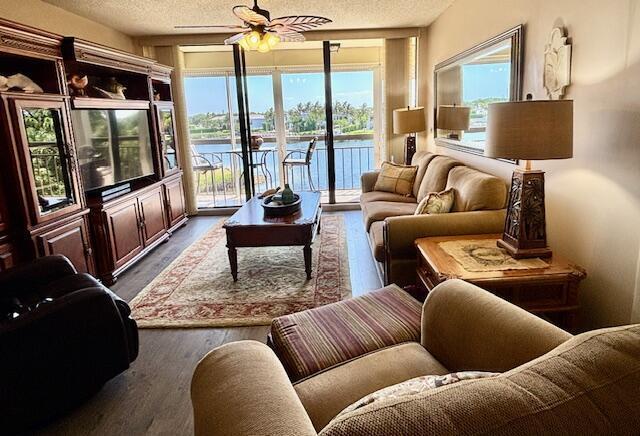 A living room features a large entertainment center, a sofa, and a balcony overlooking water — 2201 Marina Isle Way # 403, Jupiter FL 33477, JUPITER, FL