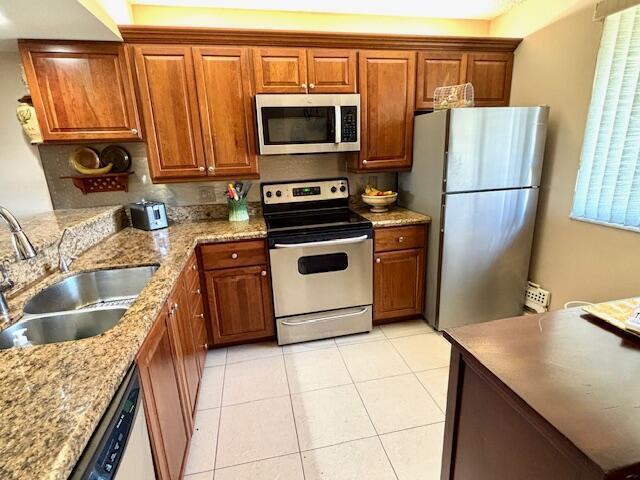 A kitchen features wood cabinets, granite countertops, stainless steel appliances, and light-colored floor tiles — 2201 Marina Isle Way # 403, Jupiter FL 33477, JUPITER, FL