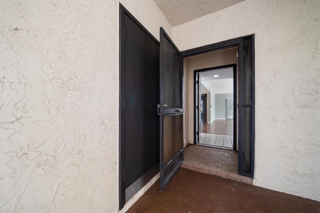An open screen door leads into a home entrance with a view of the interior — 700 STARKEY ROAD UNIT 1111, LARGO, FL