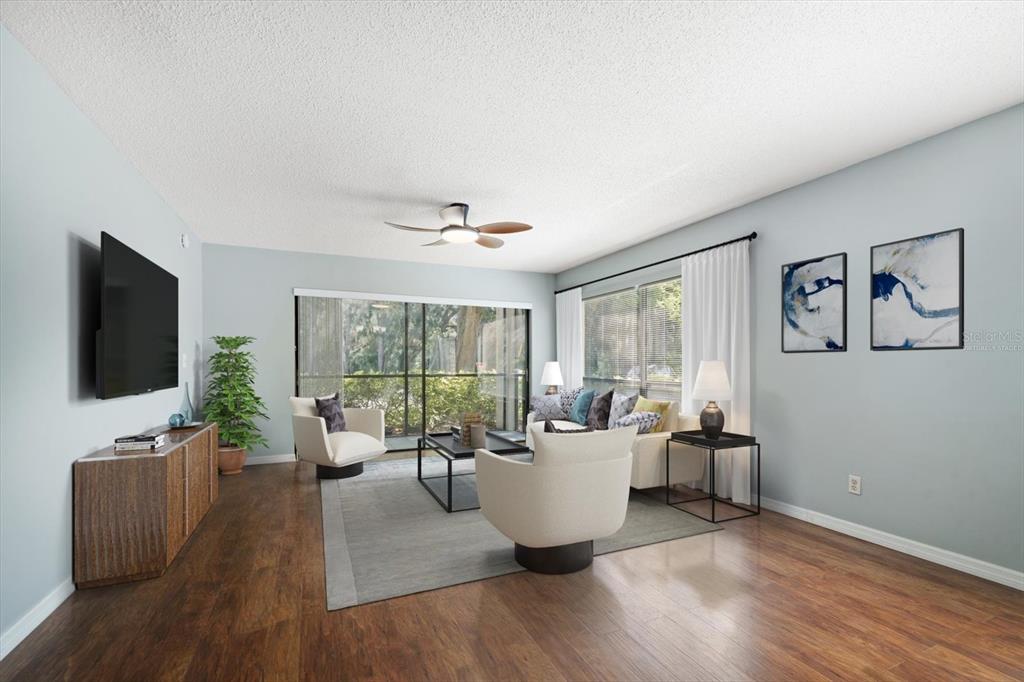 A living room features light blue walls, wood flooring, a ceiling fan, and sliding glass doors — 700 STARKEY ROAD UNIT 1111, LARGO, FL