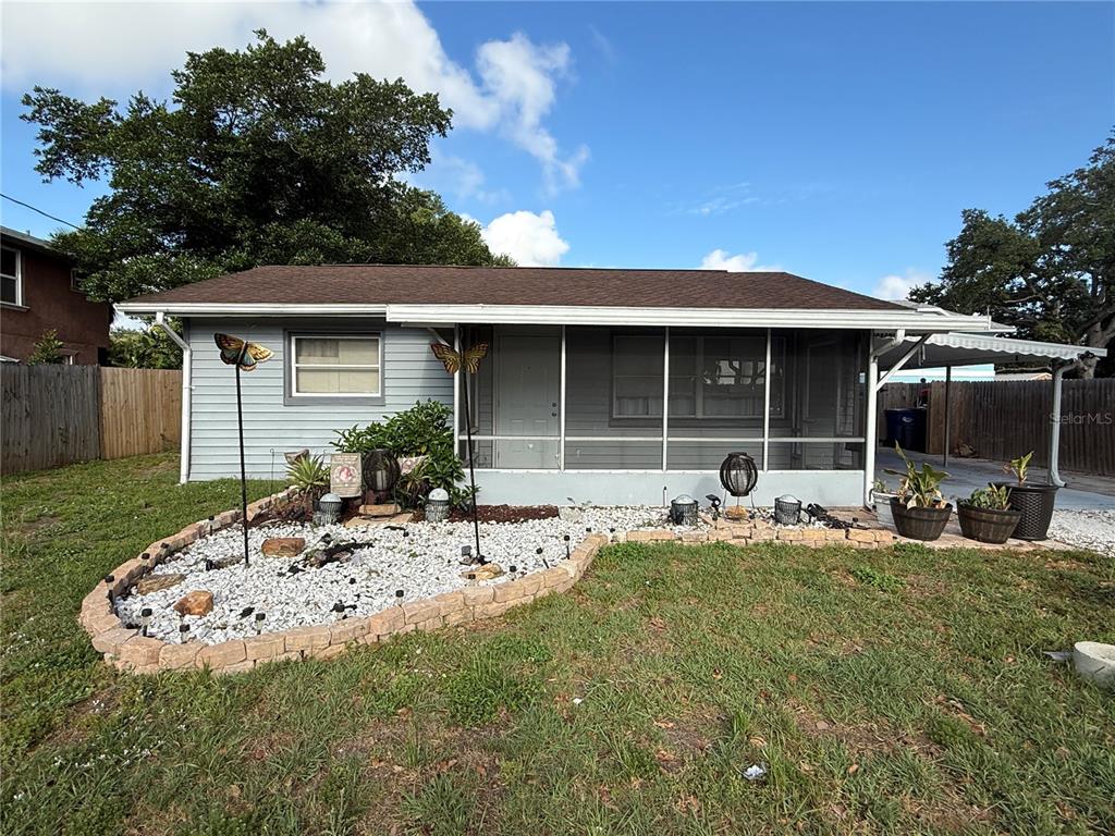 A single-story house with a screened front porch and a landscaped rock garden in front — 2402 9TH STREET E, BRADENTON, FL