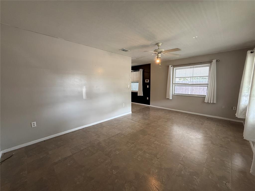 A living room with light gray walls, tile flooring, a ceiling fan, and a window — 2402 9TH STREET E, BRADENTON, FL