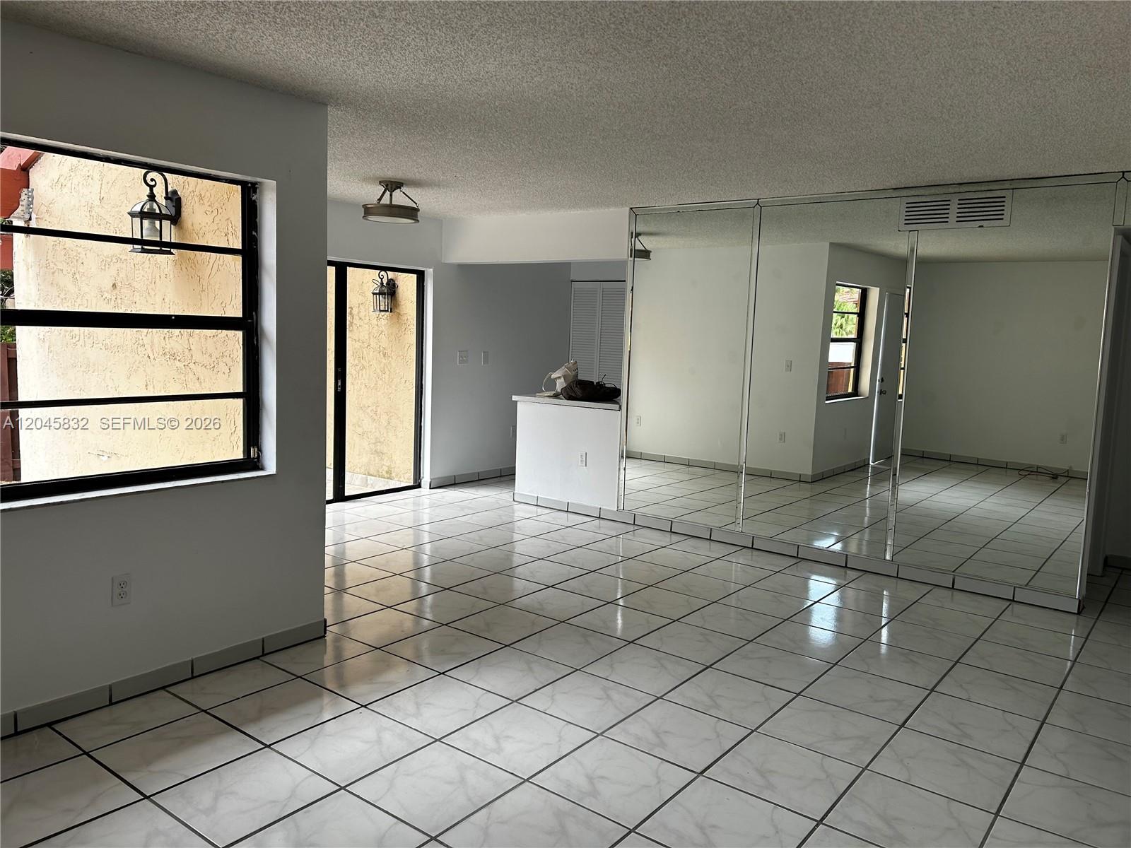 A room with white tiled floors, a mirrored wall, and a sliding glass door — 301 W Park Dr # 11, Miami FL 33172, MIAMI, FL