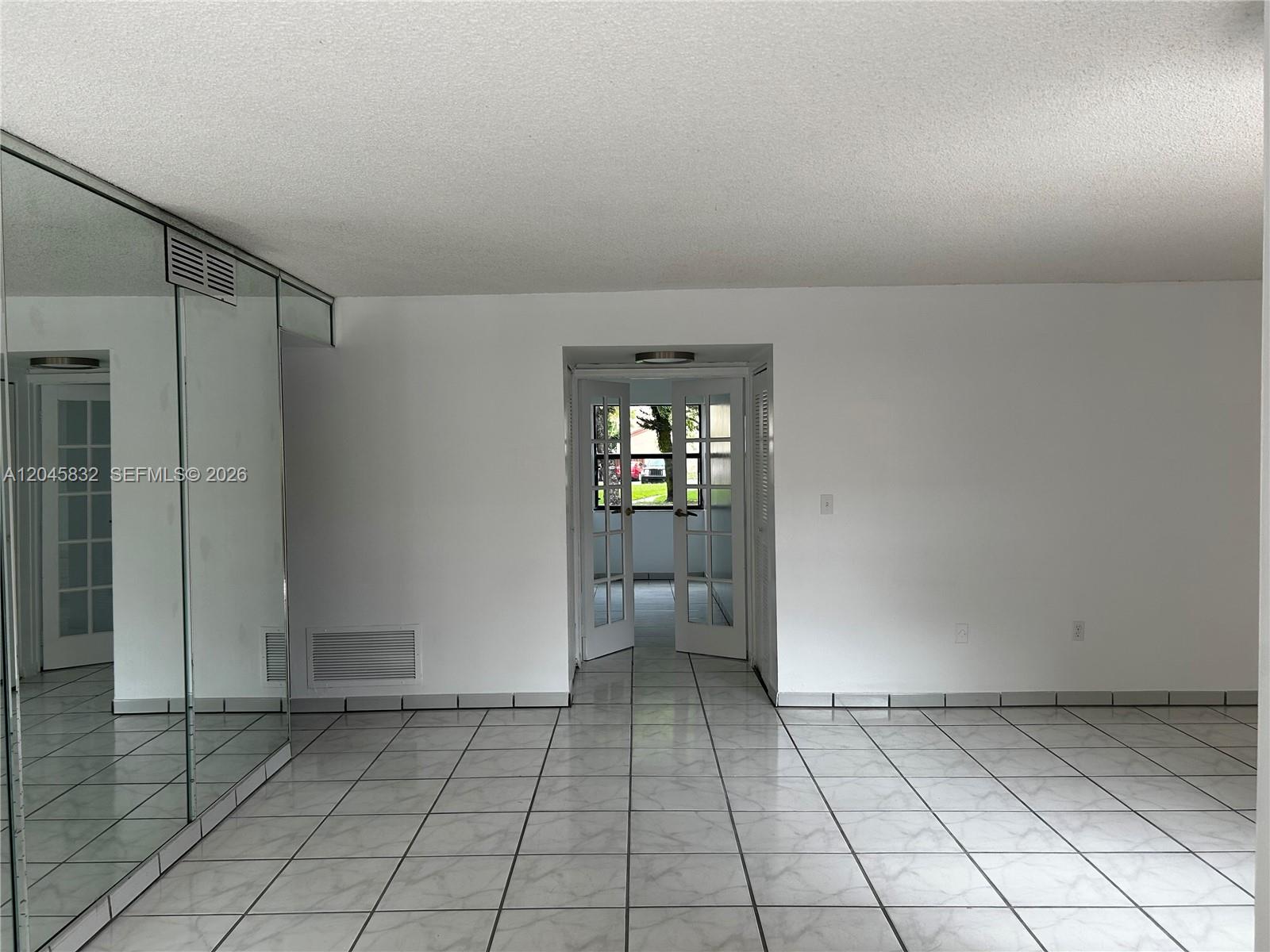 A room with white tiled floors, mirrored closet doors, and a doorway leading outside — 301 W Park Dr # 11, Miami FL 33172, MIAMI, FL