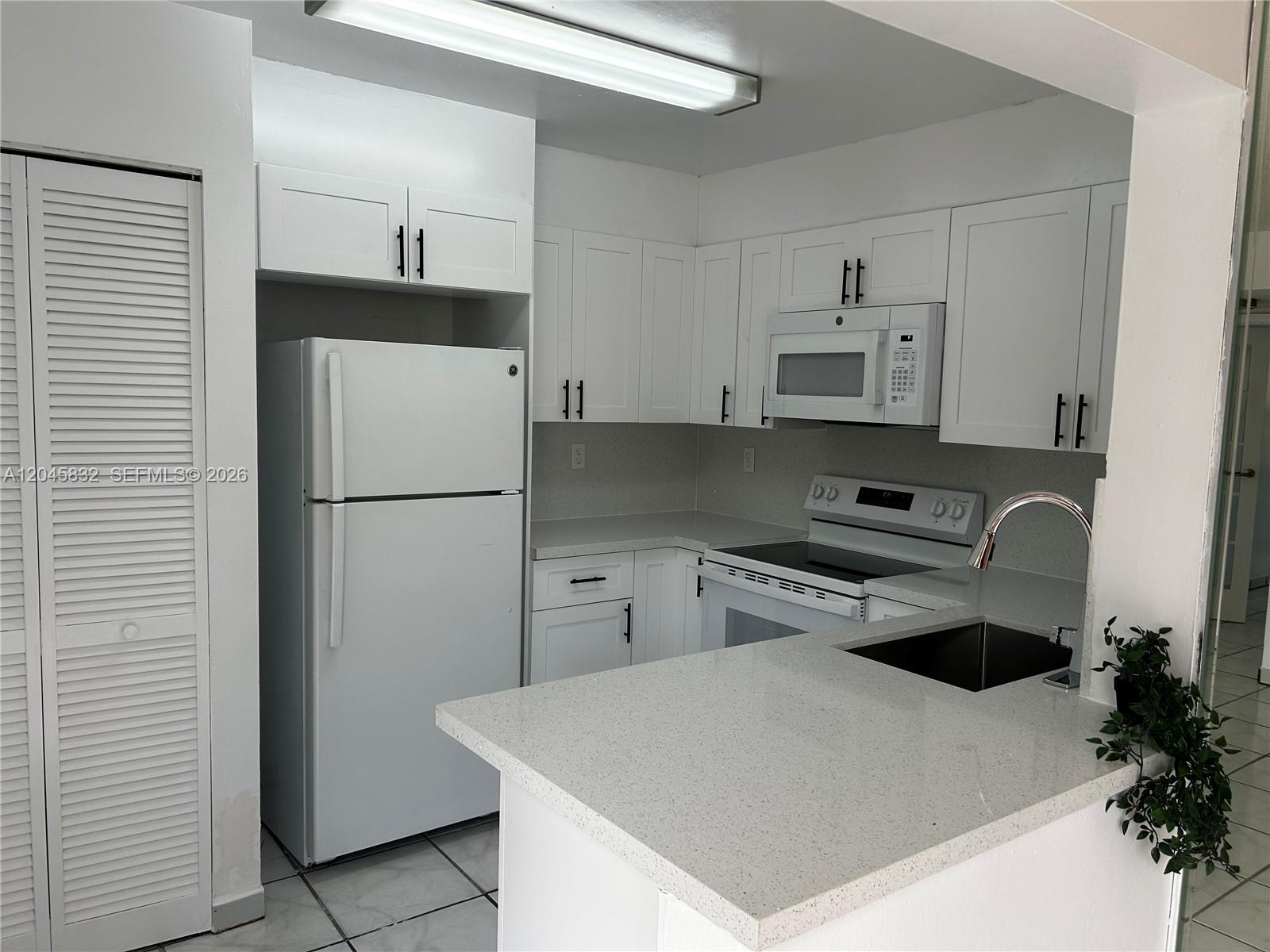 A kitchen features white cabinets, white appliances, and a light-colored speckled countertop — 301 W Park Dr # 11, Miami FL 33172, MIAMI, FL