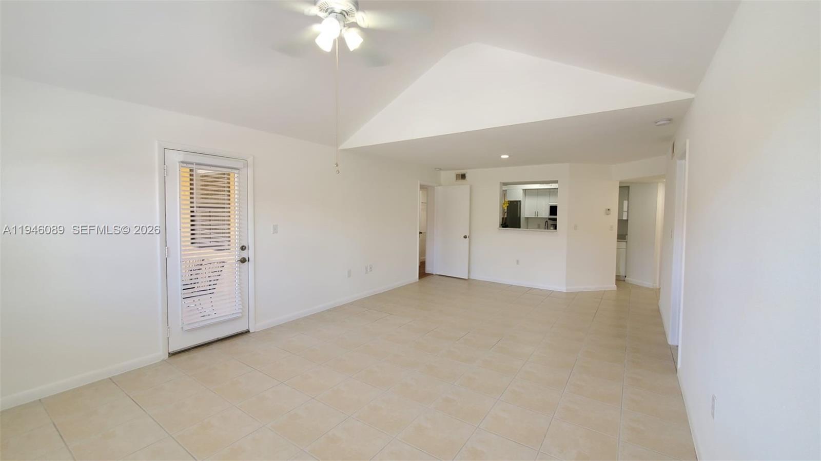 A bright living room features white walls, tile flooring, a vaulted ceiling, and a pass-through window — 10500 SW 155th Ct # 1022, Miami FL 33196, MIAMI, FL