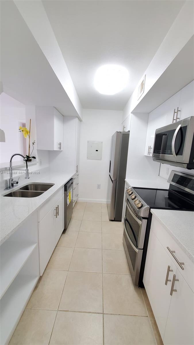 A galley kitchen features white cabinets, stainless steel appliances, and light-colored countertops — 10500 SW 155th Ct # 1022, Miami FL 33196, MIAMI, FL