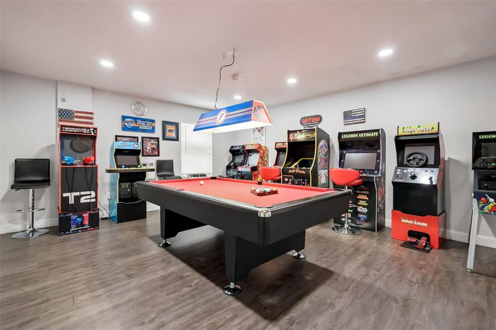 A game room features a pool table, multiple arcade cabinets, and a hanging light fixture — 948 LAKE BERKLEY DRIVE, KISSIMMEE, FL