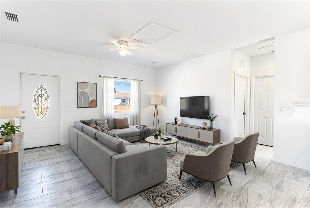A living room features a grey sectional sofa, two armchairs, a television, and tile flooring — 1407 BITTERSWEET STREET, LAKE PLACID, FL