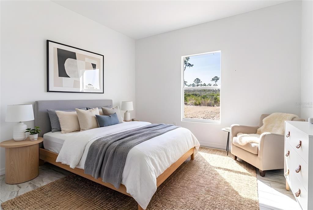 A bedroom features a bed with a grey headboard, a window, and a beige armchair — 1407 BITTERSWEET STREET, LAKE PLACID, FL