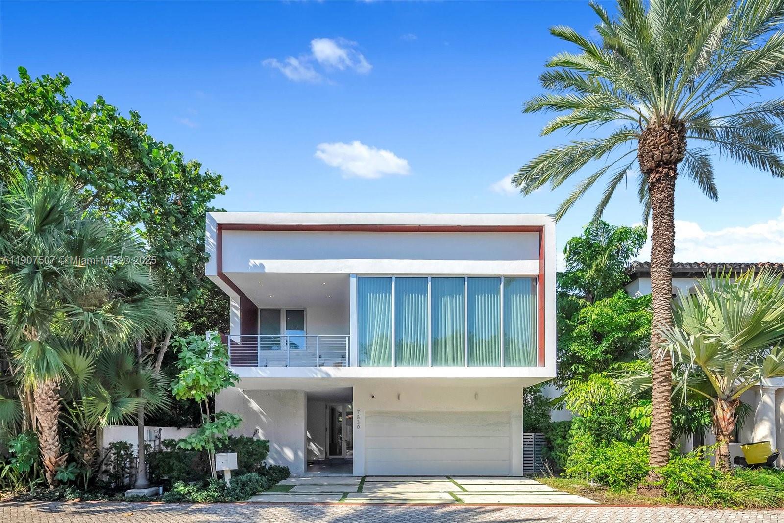 A modern two-story house features a white facade, a balcony, and a ground-level garage — 7830 Atlantic Way, Miami Beach FL 33141, MIAMI BEACH, FL