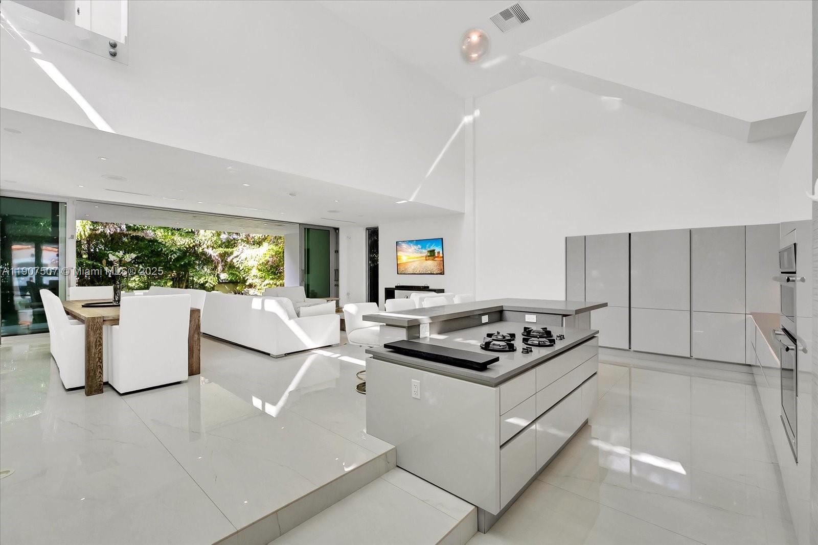 A modern, open-concept kitchen and living area features white tile floors, high ceilings, and an island — 7830 Atlantic Way, Miami Beach FL 33141, MIAMI BEACH, FL