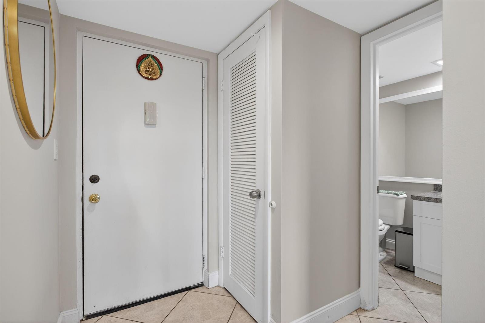 An entryway features a white door, a louvered closet door, and a doorway to a bathroom — 2314 S Cypress Bend Drive # 114, Pompano Beach FL 33069, POMPANO BEACH, FL