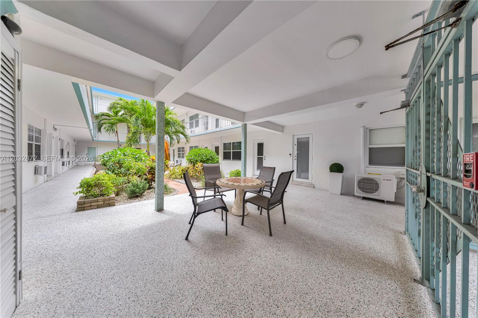 An outdoor patio area features a small table with four chairs and a garden courtyard — 260 Ocean Dr # 12A, Miami Beach FL 33139, MIAMI BEACH, FL