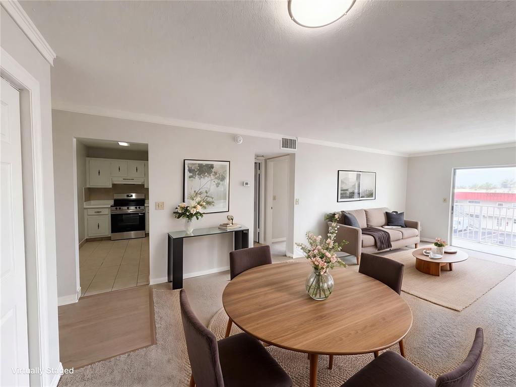 This virtually staged living and dining area features carpeted floors and an adjacent kitchen — 2711 N HALIFAX AVENUE UNIT 371, DAYTONA BEACH, FL
