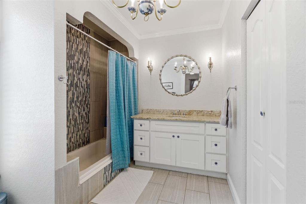 A bathroom features a white vanity with a granite countertop, a tub-shower combo, and tile flooring — 3017 N WOODROW AVENUE, TAMPA, FL
