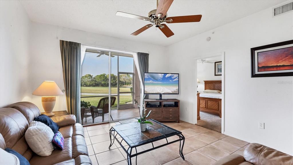 A living room with tile floors, a ceiling fan, and a sliding door to a patio — 9610 CLUB SOUTH CIRCLE UNIT 4106, SARASOTA, FL