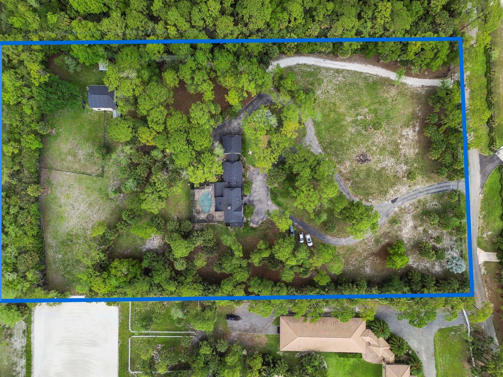 An aerial view shows a house with a pool on a large, wooded lot — 1339 Gallop Drive, Loxahatchee FL 33470, LOXAHATCHEE, FL