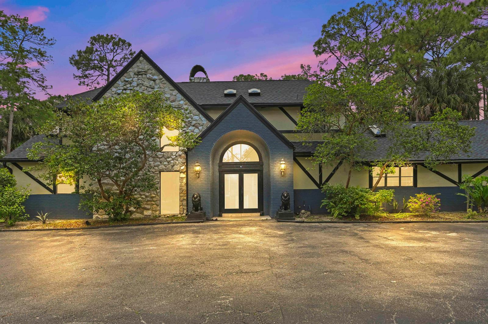A two-story house with stone and dark-painted brick siding features a prominent arched entryway — 1339 Gallop Drive, Loxahatchee FL 33470, LOXAHATCHEE, FL