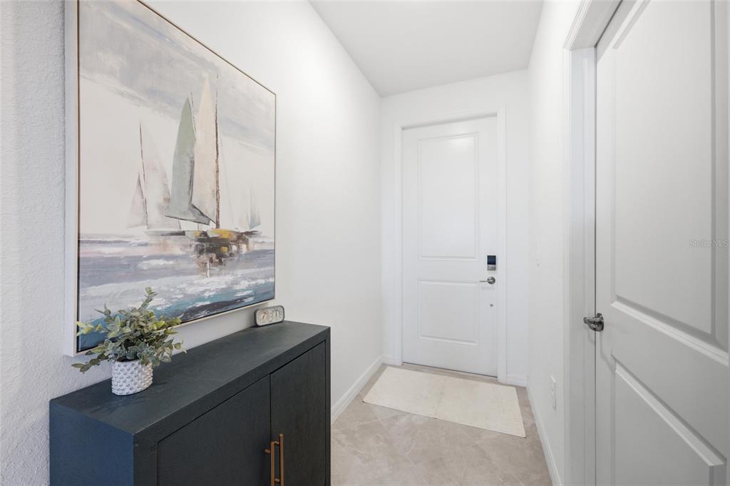 A white entryway features a black cabinet, sailboat artwork, and a door with a lock — 17595 OPAL SAND DRIVE UNIT 302, VENICE, FL