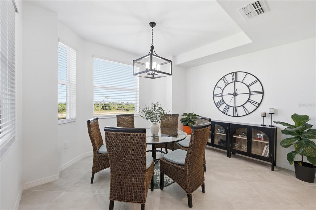 A dining area features a glass-topped table, wicker chairs, a chandelier, and a large wall clock — 17595 OPAL SAND DRIVE UNIT 302, VENICE, FL