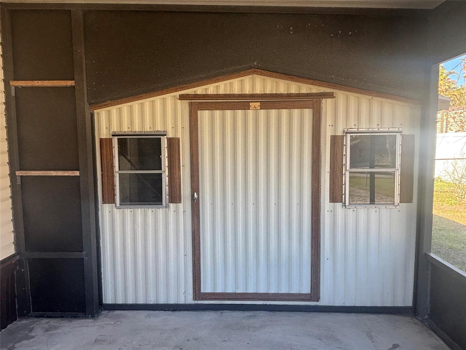 A metal storage shed with a central door and two windows sits under a roof — 4968 Amy Lane, Fort Pierce FL 34946, FORT PIERCE, FL