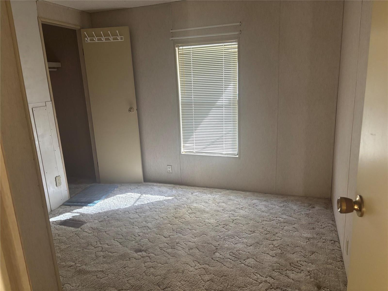 A bedroom with beige paneled walls, carpeted flooring, a window with blinds, and a closet — 4968 Amy Lane, Fort Pierce FL 34946, FORT PIERCE, FL