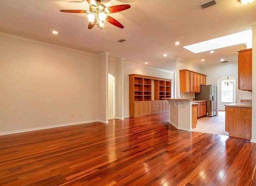 A spacious living area with hardwood floors, a ceiling fan, and an adjacent open kitchen — 7962 SW 85TH TERRACE, GAINESVILLE, FL