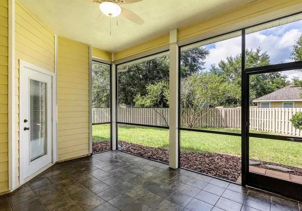 A screened-in porch with yellow siding, tile flooring, and a ceiling fan overlooks a backyard — 7962 SW 85TH TERRACE, GAINESVILLE, FL