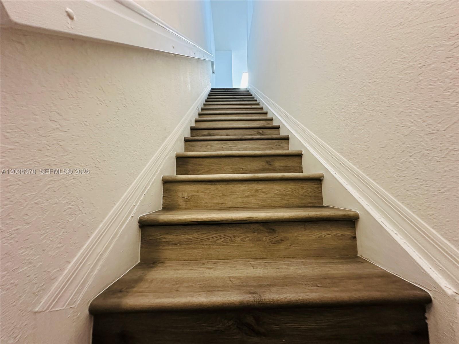 A straight wooden staircase with white walls leads upward to a bright landing — 5705 NW 109th Ave # 50, Doral FL 33178, DORAL, FL